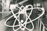 Men preparing the stage for the conference. 
One of them is holding a giant mock-up of an atom. 
(IAEA Archives/Credit: Photo Ellinger)