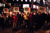 10 December 2005 | The people of Oslo gather outside the laureate's hotel to watch them wave from the balcony.  They carry signs of protest against nuclear weapons.